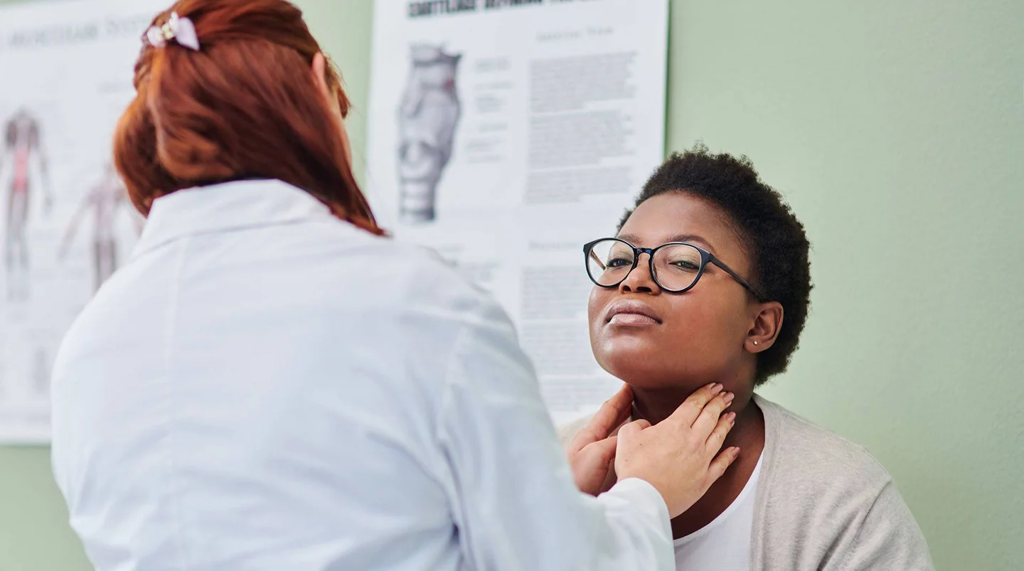 Eine Ärztin untersucht die Lymphknoten am Hals einer jungen Patientin.