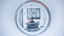 CUP-Syndrom (Krebs bei unbekanntem Prim&auml;rtumor): Ein Patient liegt vor einer MRT-R&ouml;hre. Im Hintergrund steht eine &Auml;rztin hinter einer Glasscheibe und beobachtet den Patienten.