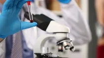 Eine Hand in Medizinhandschuhen h&auml;lt ein R&ouml;hrchen, in dem eine Blutprobe zur Untersuchung auf H&auml;mophilie ist. 