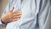 Gastro&ouml;sophageale Refluxerkrankung: Eine Person dr&uuml;ckt ihre rechte Hand auf den Brustkrob.