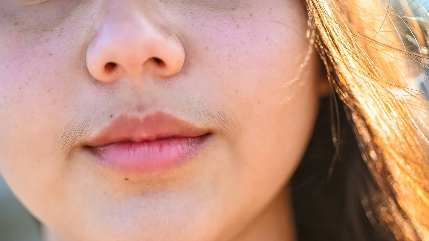 Nahaufnahme: Gesicht einer jungen Frau mit einem sogenannten Damenbart.