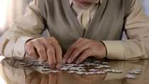 Ein älterer Herr sitzt an einem Tisch und puzzelt.