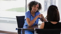 Eierstockkrebs: Eine Ärztin und eine Patientin sitzen an einem Tisch. Die Ärztin spricht mit der Patientin.
