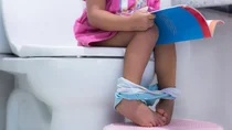Ein kleines Kind sitzt auf der Toilette. Seine F&uuml;&szlig;e stehen auf einem H&ouml;ckerchen.