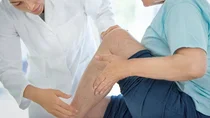Ärztin untersucht den Unterschenkel eines Patienten.