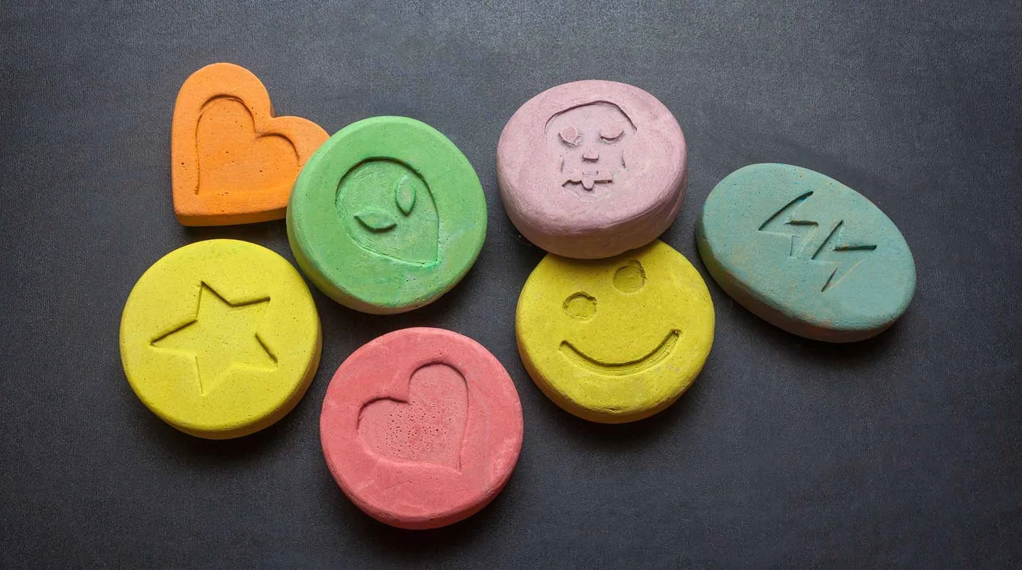 Bunte Pillen mit Symbolen wie Herz, Stern oder Smiley.
