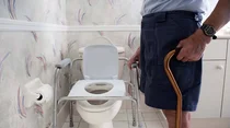 Mann mit Gehstock vor einer behindertengerechten Toilette