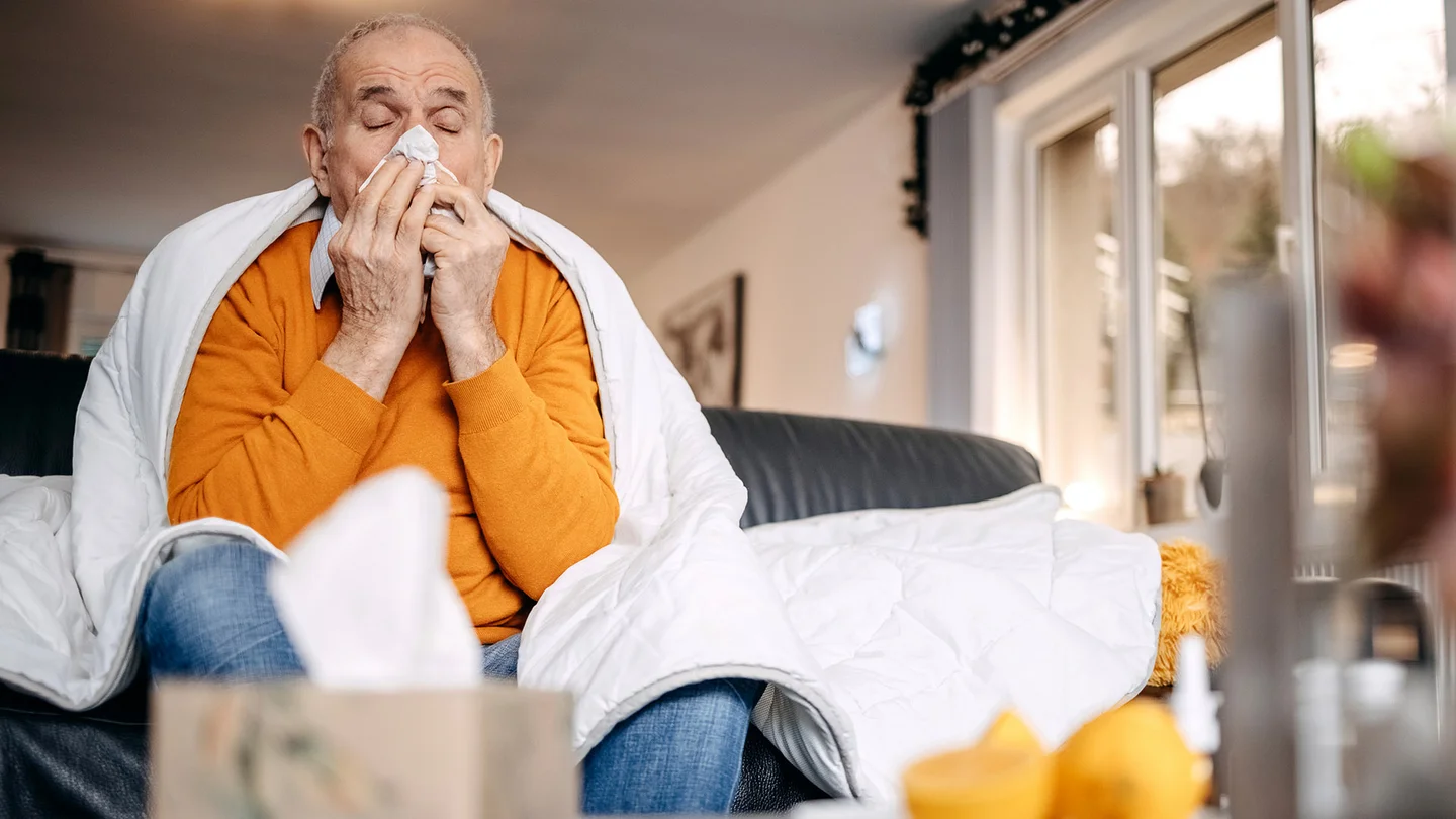 Ein Mann sitzt mit Erkältung zu Hause.
