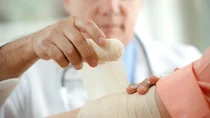 Ein Arzt umwickelt einen Arm mit einer Mullbinde