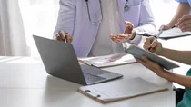 Medizinisches Personal zeigt sich an einem Laptop gegenseitig Forschungsergebnisse.
