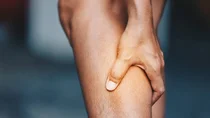 Eine Hand greift an die Wade.