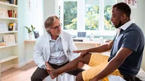 Arzt untersucht das Fu&szlig;gelenk eines Patienten