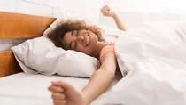 Eine Frau liegt im Bett und räkelt sich.