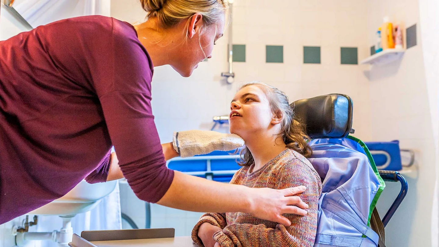 Eine Frau betreut ein junges Mädchen in einem elektronischen Rollstuhl.