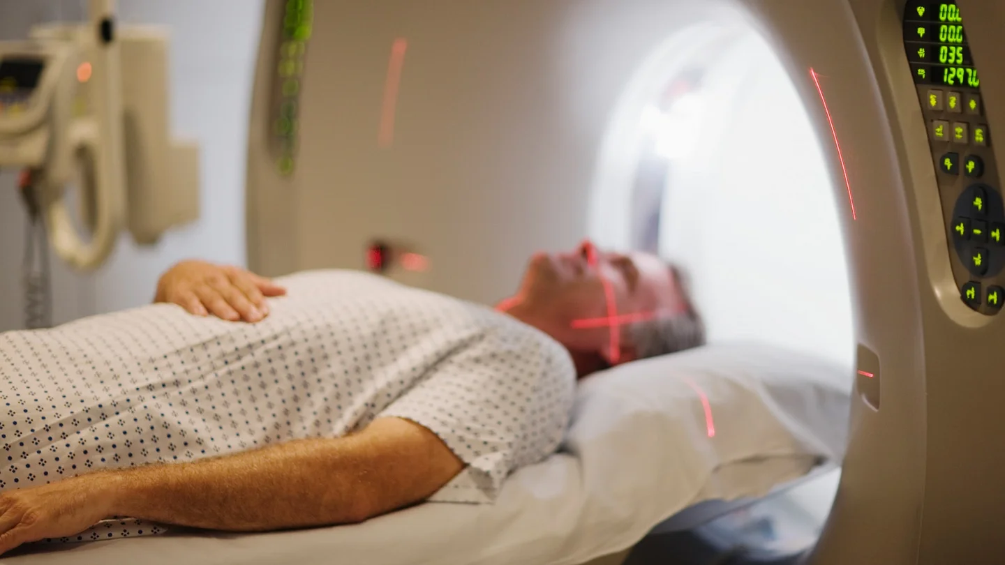 Multiples Myelom: Ein Mann liegt in einer MRT-R&ouml;hre. &Uuml;ber seinem Gesicht verlaufen zwei rote Laser.