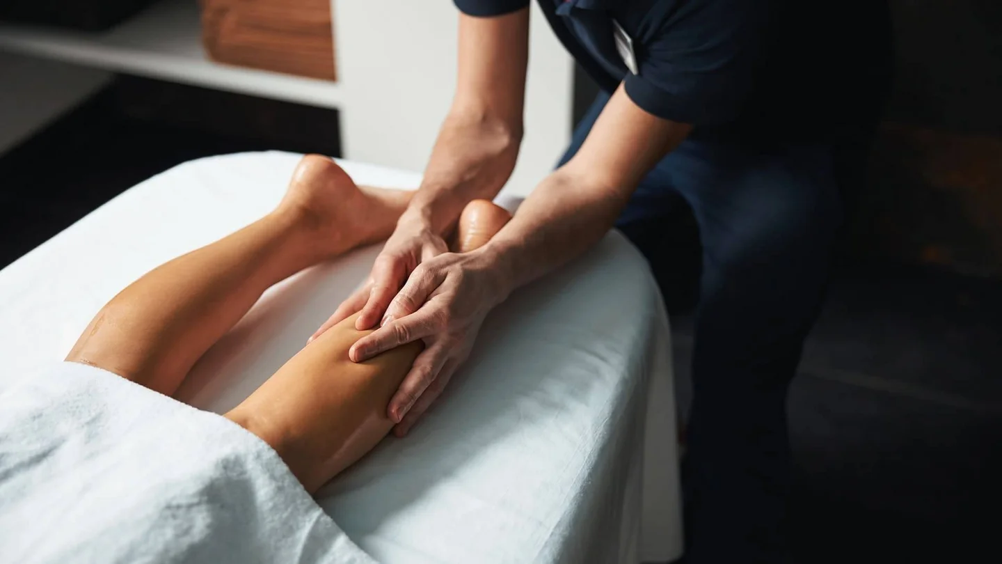 Ein Physiotherapeut massiert die Beine einer Patientin, damit die gestaute Lymphe abflie&szlig;en kann.