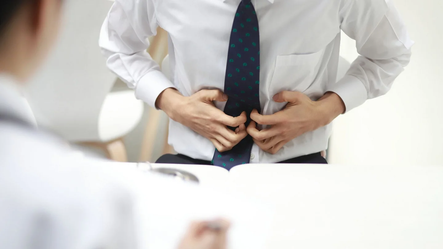 Magenkrebs: Ein Mann greift sich mit beiden Händen an den Bauch. Er scheint starke Schmerzen zu haben.