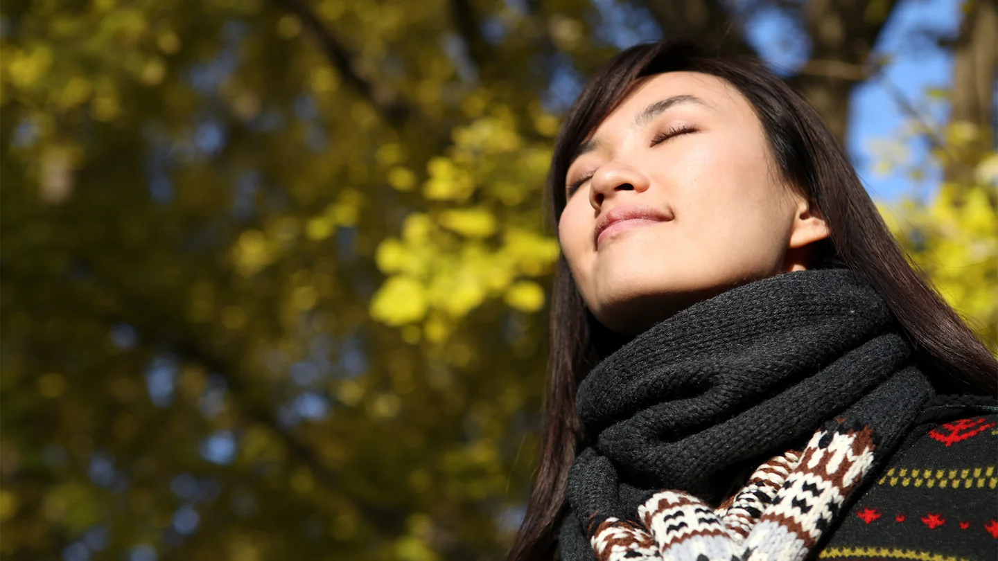 Eine junge Frau hält ihr Gesicht in die Sonne.