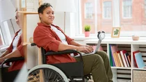 Frau sitzt im Rollstuhl mit Laptop auf dem Scho&szlig;.