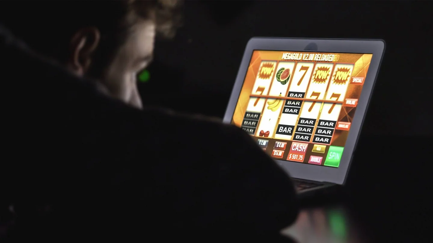 Ein Mann spielt Gl&uuml;cksspiel an einem Computer.