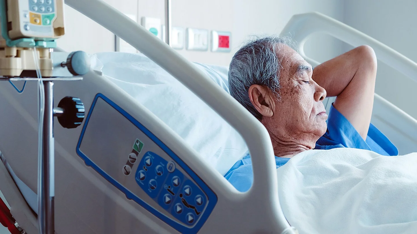 Ein älterer Mann liegt in einem Krankenhausbett.
