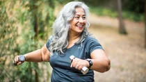 Diabetes Typ 2: Eine Frau h&auml;lt Hanteln in beiden H&auml;nden, ist sportlich aktiv und l&auml;chelt.