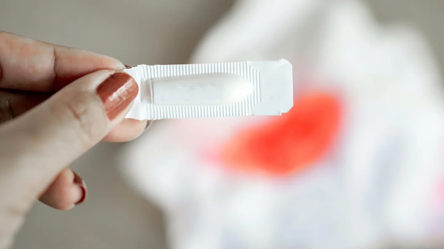 Frau hält verpacktes Vaginalzäpfchen in der Hand.