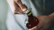 Eine Bierflasche wird mit einem Flaschen&ouml;ffner ge&ouml;ffnet.