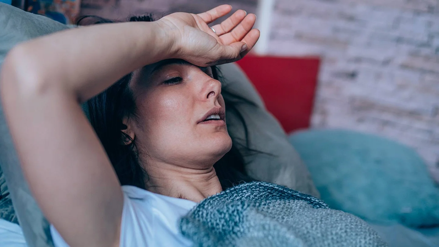 Eine Frau liegt erschöpft auf der Couch.