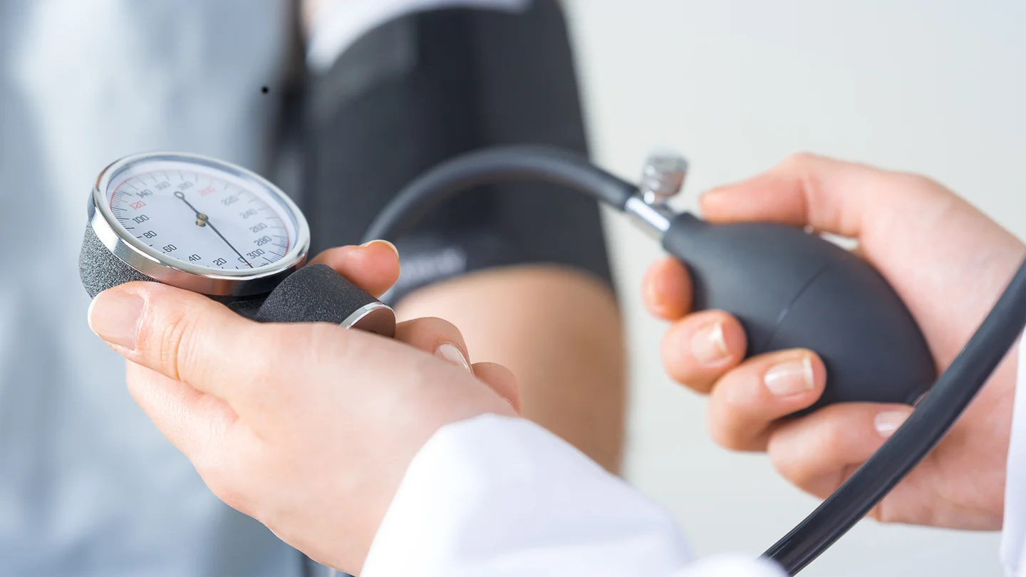 Zwei H&auml;nde halten ein Blutdruckmessger&auml;t um den Bluthochdruck eines Patienten zu messen.