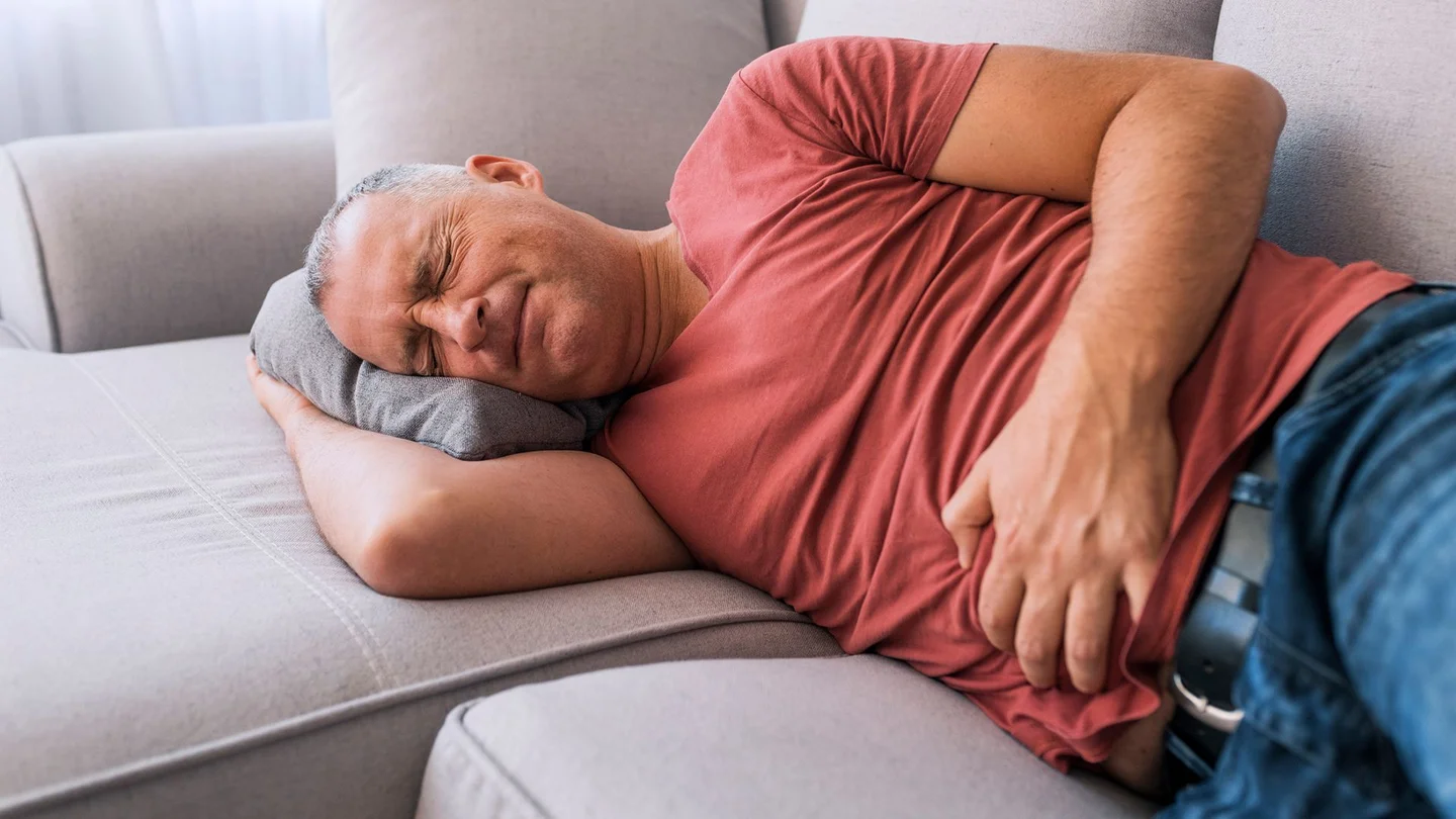 Darmkrankheit Divertikulitis: Ein Mann h&auml;lt sich mit beiden H&auml;nden den Bauch.