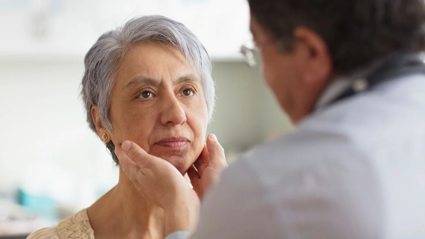 Hodgkin-Lymphom: Eine Frau wird von einem Arzt am oberen Hals unter dem Kinn abgetastet.