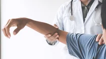 Eine Person mit Arztkittel und umgeh&auml;ngtem Stethoskop untersucht den Arm eines Patienten, indem sie Schulter und Ellbeuge fasst und augenscheinlich leicht bewegt.