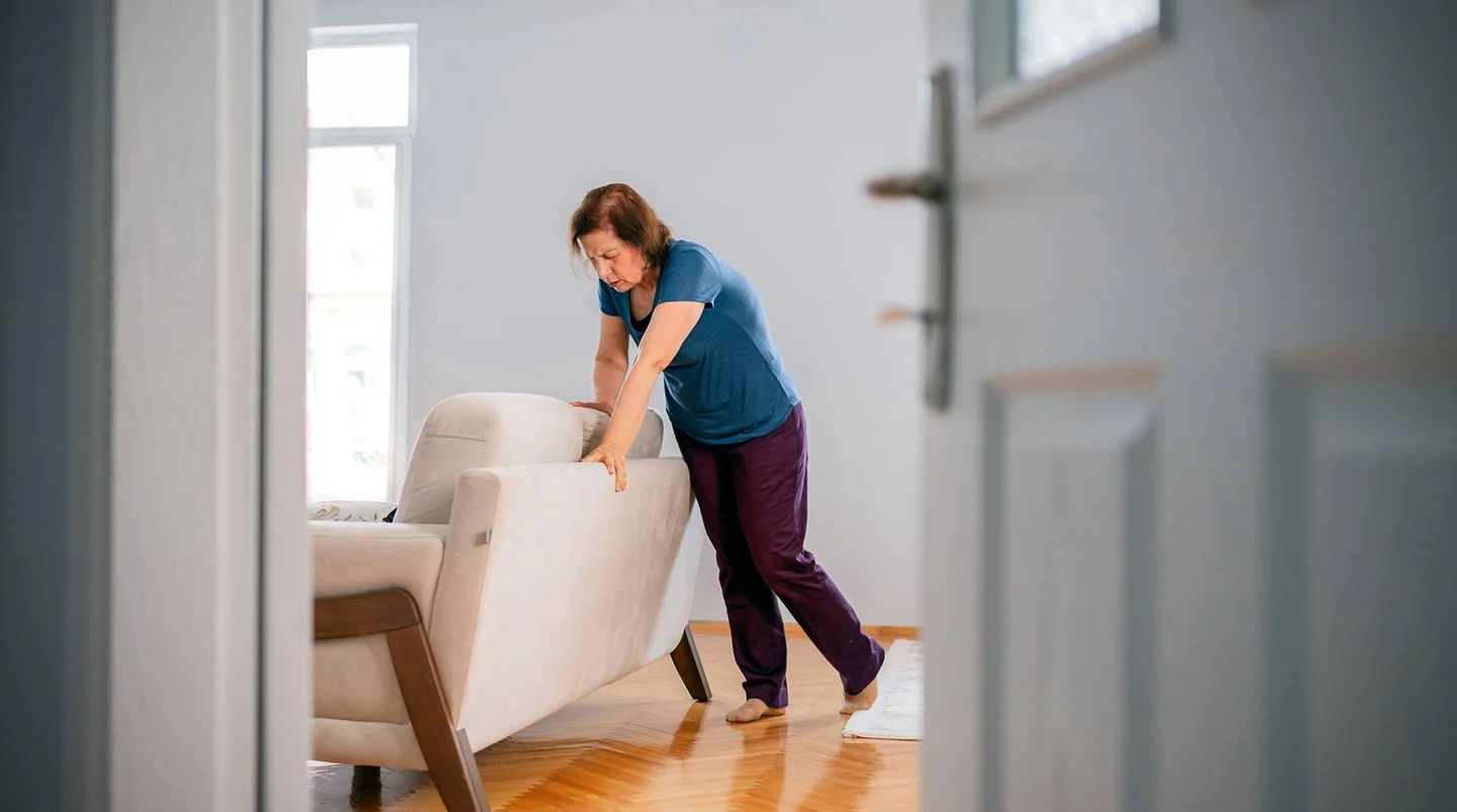 Eine Frau st&uuml;tzt sich mit Schwindelgef&uuml;hlen auf der Couch ab.