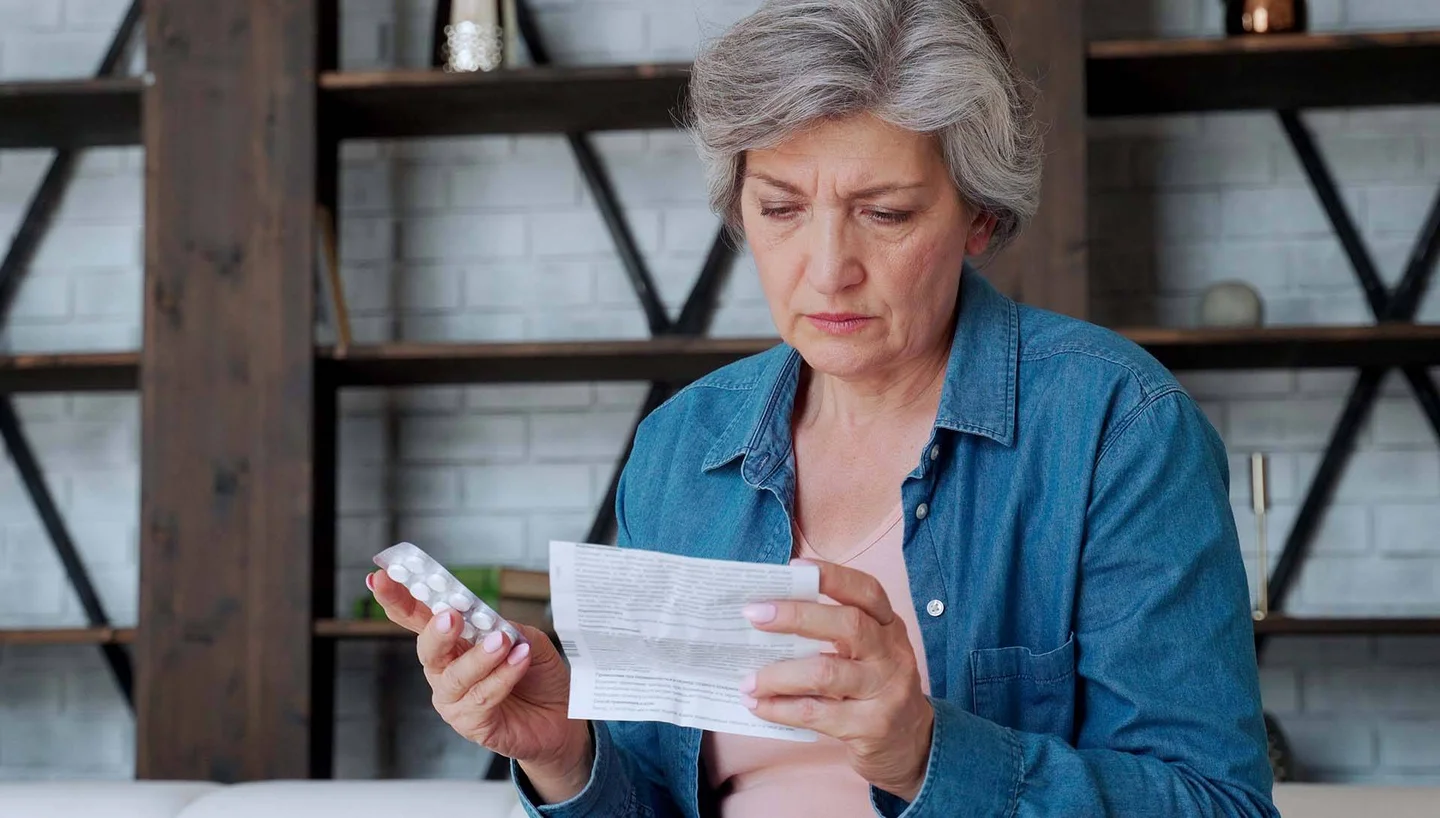 Frau liest den Beipackzettel eines Arzneimittels.