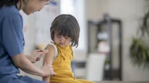 Impfungen: Einem kleinen M&auml;dchen wird von einer Krankenpflegerin ein Pflaster auf den Oberarm geklebt.