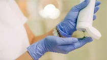 Eine Frau mit Einmalhandschuhen trägt ein Gel auf. 
