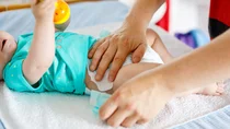 Einem Baby wird eine Windel angelegt.