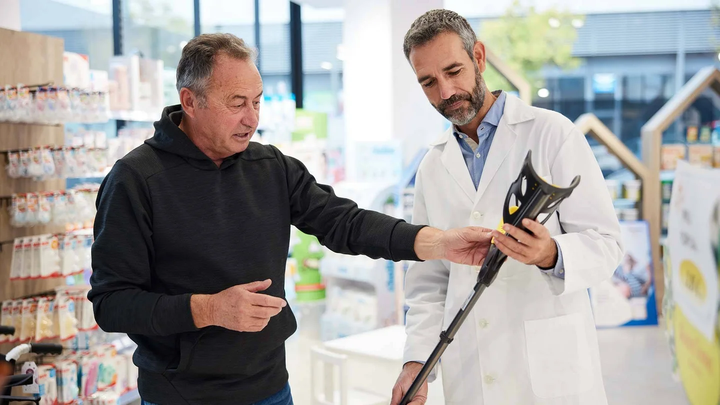 Verk&auml;ufer und Kunde mit einer Gehhilfe.